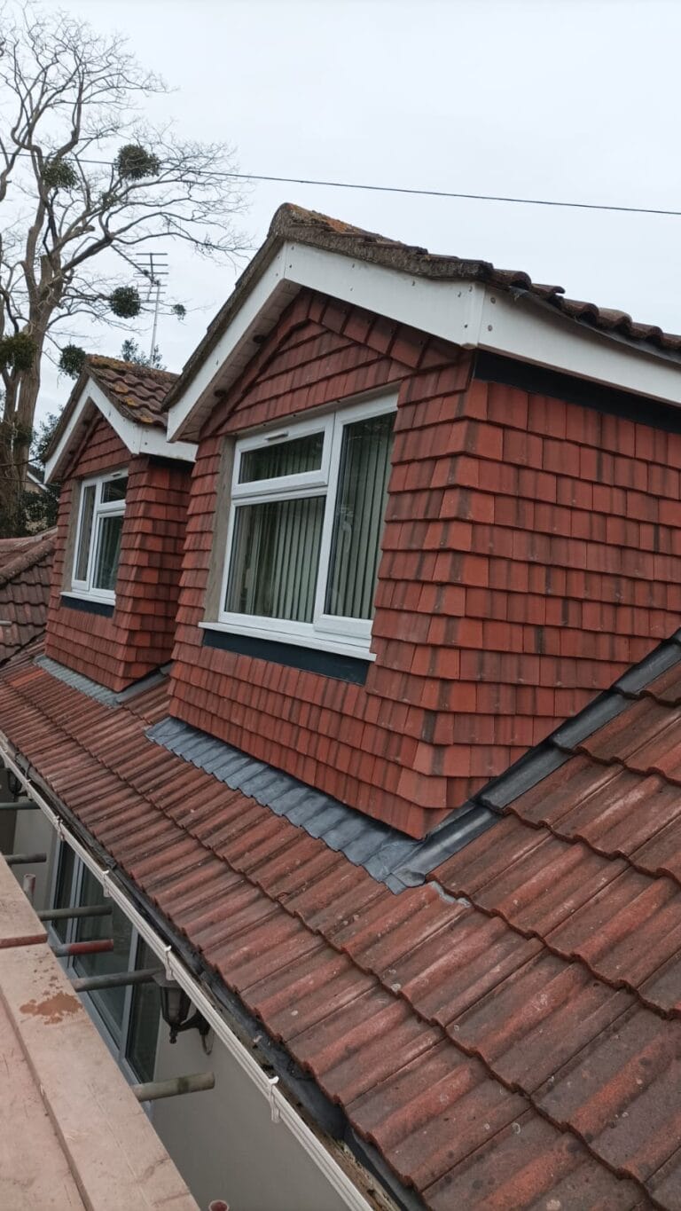 dormer window with red tile-hung cladding, white bargeboard, and pitched roof with clay tiles